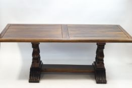 A modern stained oak dining table on a heavily carved baluster supports and scroll footed base,