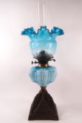 A Victorian glass oil lamp with moulded blue glass reservoir, frilled shade and funnel,