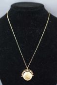 A spinning round locket pendant with fine link chain, gold plated. 5.