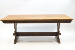 A modern oak refectory style dining table with decoratively carved apron and stretcher,