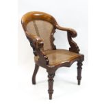 A Victorian mahogany bergere armchair with scroll arms on turned front legs