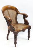 A Victorian mahogany bergere armchair with scroll arms on turned front legs