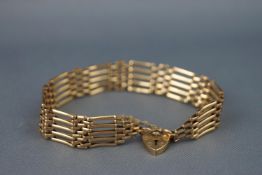 A yellow metal five bar and basket gate bracelet with padlock and safety chain.