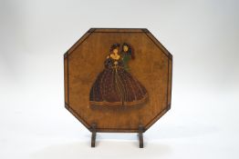 An Art Deco octagonal wooden fire screen, mounted with a flirting couple in period costume,