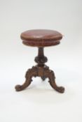 A Victorian walnut adjustable piano stool with leather seat,
