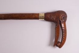 A walking stick, the handle being a toucan with a nut in its beak,