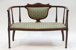 An Edwardian mahogany salon settee with inlaid flower detail to crest rail,