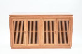 A modern teak sideboard with pole fronted cupboard doors,