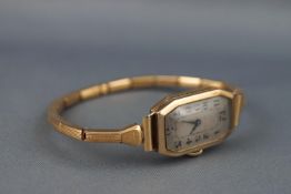 A yellow metal ladies wrist watch. Rectangular dial with numerical markings.