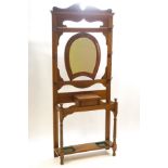 An early 20th century oak hallstand with central horseshoe shape mirror over a lidded storage box