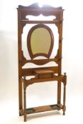 An early 20th century oak hallstand with central horseshoe shape mirror over a lidded storage box