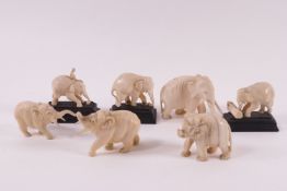 A collection of seven early 20th century carved ivory elephants, three on wooden stands,