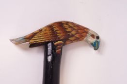 A wooden walking stick with carved and painted eagle handle