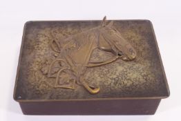 A rectangular wooden box with a horses head and riding motifs in relief,