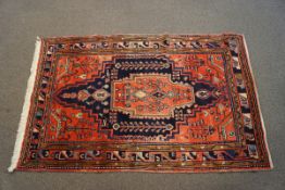A modern Middle Eastern rug with central medallion of stylised flowers on a red field within