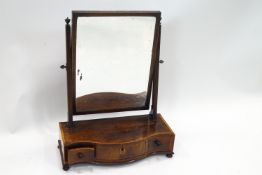 A George III mahogany swing framed mirror on serpentine box base with three drawers on ball feet,