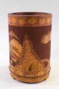 A Chinese carved bamboo brush pot on three feet, decorated with a figure in a continuous landscape,