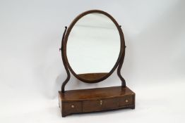 A 19th century oval mahogany swing frame mirror on box base with three drawers on bracket feet,