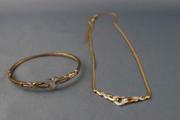 A yellow and white metal necklace and bangle stylized as a centrepiece with heart motif and