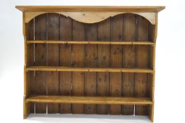 A pine plate rack with three shelves, shaped cornice and sides,