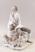 A Lladro porcelain figure of a seated shepherd with his dogs and a sheep at his feet,