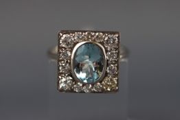 A white metal cluster ring with central aquamarine (approx 1.