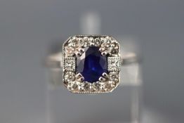 A white metal cluster ring set with central oval sapphire (approx 1.