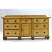 A Victorian pine dresser base with raised back and an arrangement of drawers with turned handles,