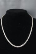 A white metal graduated diamond line necklace set with one hundred and twenty five round brilliant