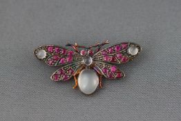 A yellow and white metal butterfly brooch set with cabochon moonstone and faceted rubies.