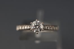 A white metal single stone diamond ring with diamond shoulders. Hallmarked 18ct gold, Birmingham.