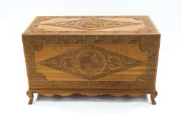 A teak chest, carved with repeating geometric designs with shaped apron and cabriole legs,