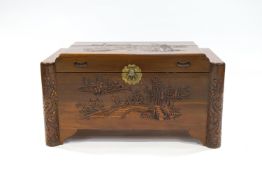 A Chinese camphor wooden chest, carved with figures on a bridge with boats on the river beyond,