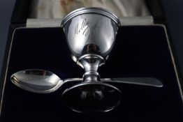 A silver christening egg cup and spoon, cased, both inscribed, London 1921,