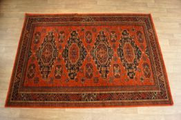 A large hand made carpet with four medallions on a red field within multiple borders 171cm x 240cm