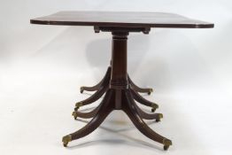 A mahogany Regency style dining table with one loose leaf and twin pedestals,