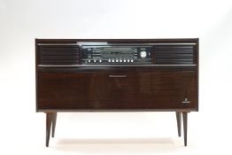 A Grundig radiogram with record player in the cabinet below, on tapering legs,
