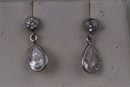 A white metal pair of drop earrings set with colourless cubic zirconia.