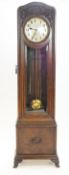A 1930's oak longcase clock with repeater chiming mechanism, the case carved with flowers and fruit,