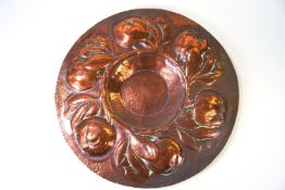A copper Arts & Crafts style wall plate, hammered with a wide rim of fruiting branches,