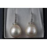 A white metal pair of drop earrings each having a peardrop South Sea pearl (13.