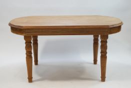 A modern teak oval ended dining table on turned legs,