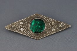 An Arts and Crafts brooch with white metal textured mount and green resin centre 11.