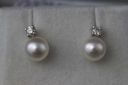 A white metal two stone pair of cultured pearl and diamond stud earrings.