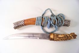A Balinese knife with carved bone handle, and white metal mounted scabbard,
