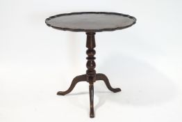 A George III style mahogany tripod table, the top with piecrust edge, on turned column and pad feet,