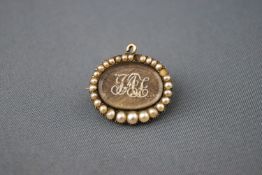 A 19th century gold and half pearl mourning brooch with plaited hair and pearl set initials.