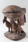 A carved wood ethnographic domed lidded bowl raised on two birds 21 x 27 cms
