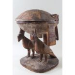 A carved wood ethnographic domed lidded bowl raised on two birds 21 x 27 cms