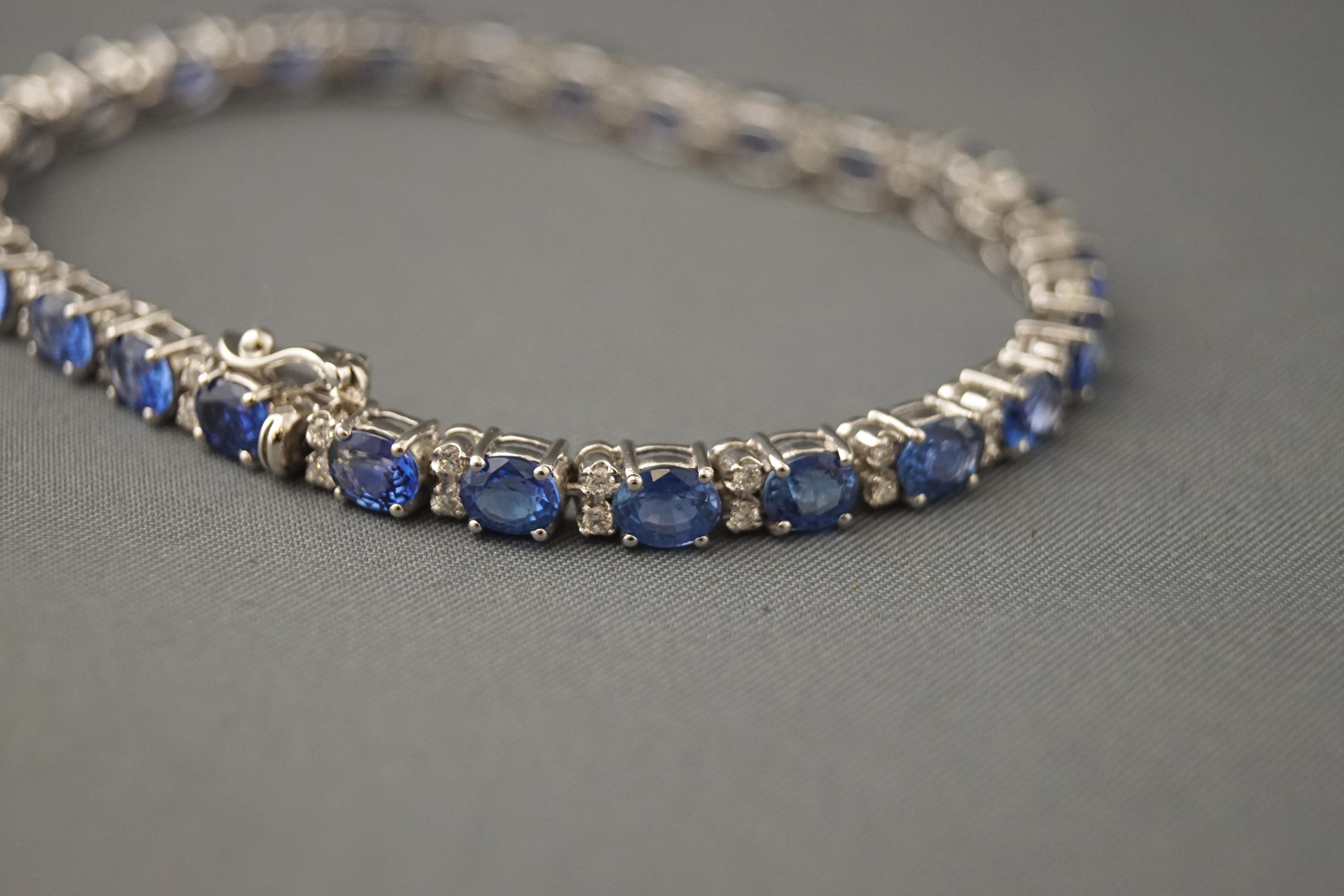 A white metal line bracelet set with oval faceted blue sapphires. - Image 2 of 2